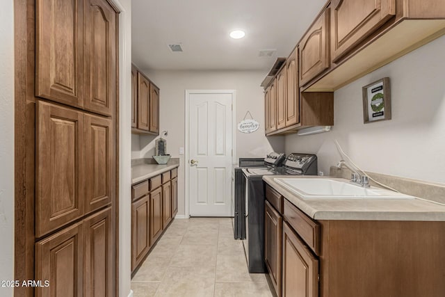 clothes washing area with cabinet space, light tile patterned floors, visible vents, independent washer and dryer, and a sink