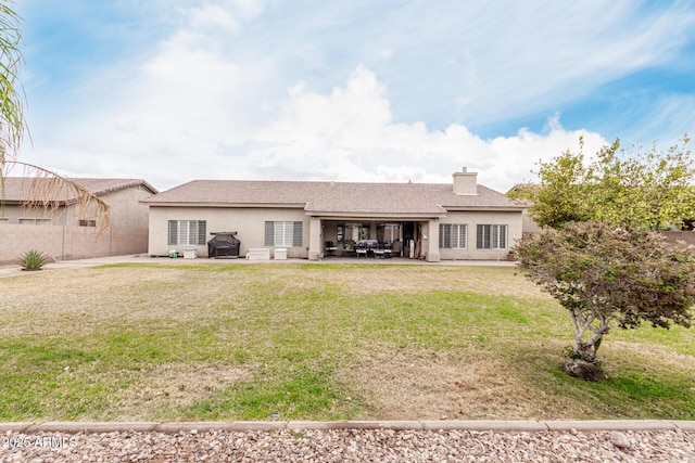 back of property with a chimney, a patio, a lawn, and stucco siding