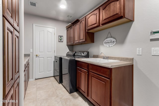 washroom with washing machine and clothes dryer, visible vents, cabinet space, a sink, and light tile patterned floors