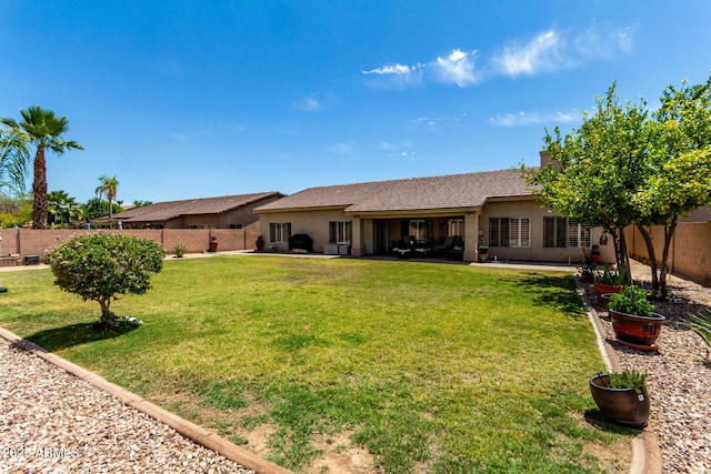 rear view of property with a fenced backyard, stucco siding, a lawn, and a patio area