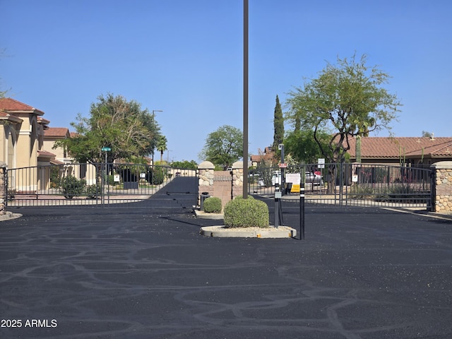view of street featuring a gate, a gated entry, and curbs