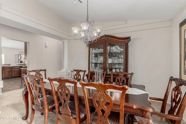 dining room with ornate columns, light tile patterned floors, light colored carpet, and an inviting chandelier