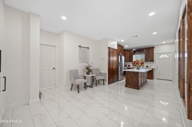 kitchen with a barn door, a kitchen island, and stainless steel refrigerator with ice dispenser