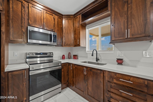 kitchen with sink, dark brown cabinetry, stainless steel appliances, and light tile patterned floors