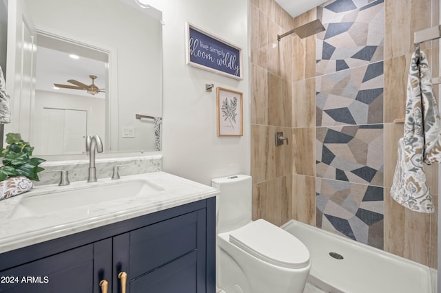 bathroom with toilet, ceiling fan, vanity, and tiled shower