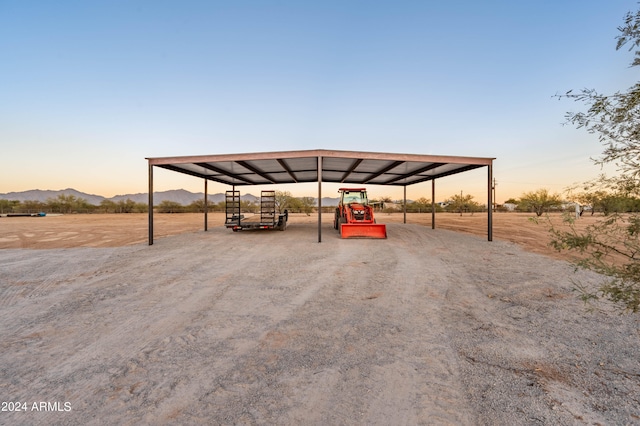 parking at dusk featuring a mountain view and a carport