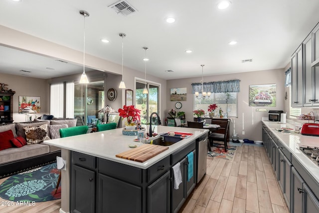 kitchen with sink, an island with sink, dishwasher, and decorative light fixtures