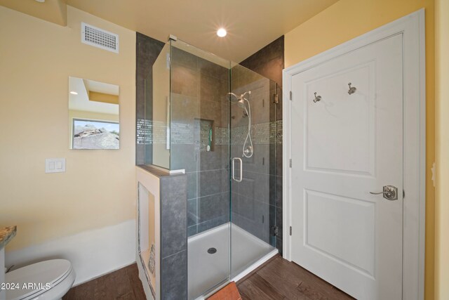 bathroom featuring an enclosed shower, hardwood / wood-style floors, and toilet