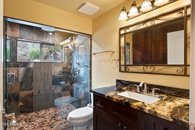 bathroom featuring vanity, a shower with shower door, and toilet