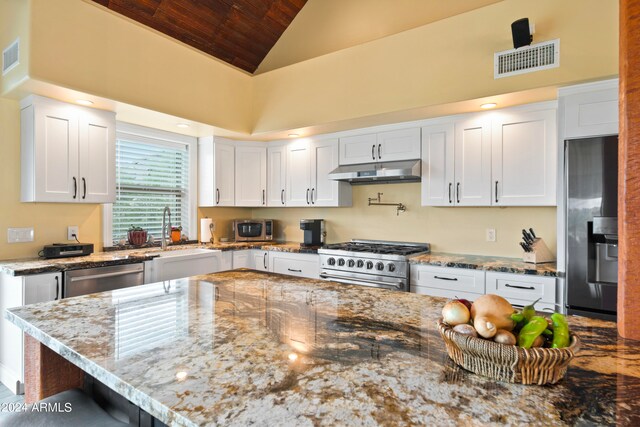 kitchen featuring sink, a breakfast bar, stainless steel appliances, light stone countertops, and white cabinets