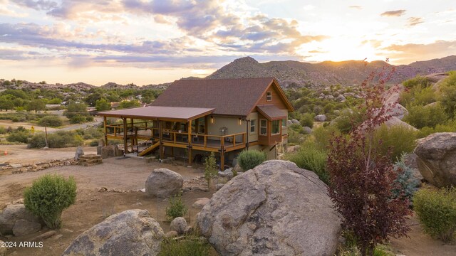 back house at dusk with a deck with mountain view