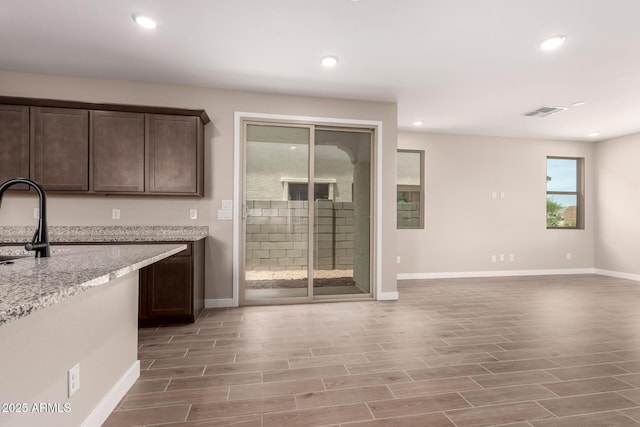 15599 S 180th Ln, Goodyear, AZ 85338 - kitchen featuring baseboards, dark brown cabinetry, light wood-style flooring, recessed lighting, and light stone countertops