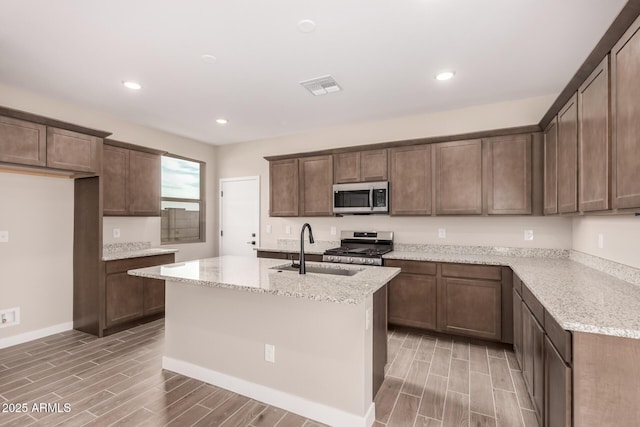 15599 S 180th Ln, Goodyear, AZ 85338 - kitchen with appliances with stainless steel finishes, a sink, wood finish floors, light stone countertops, and recessed lighting