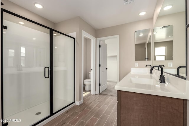15599 S 180th Ln, Goodyear, AZ 85338 - full bathroom featuring toilet, double vanity, a stall shower, wood finished floors, and baseboards