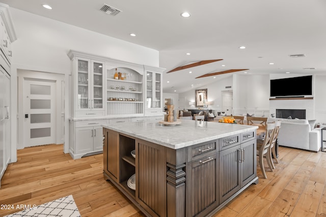 kitchen featuring light hardwood / wood-style flooring, a kitchen island, lofted ceiling, and white cabinetry