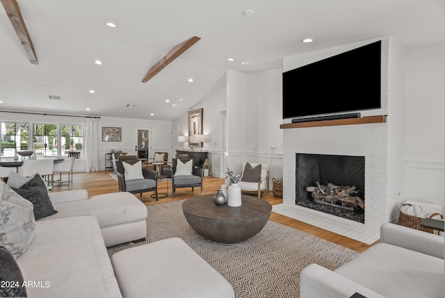 living room featuring lofted ceiling with beams, light hardwood / wood-style flooring, and a fireplace