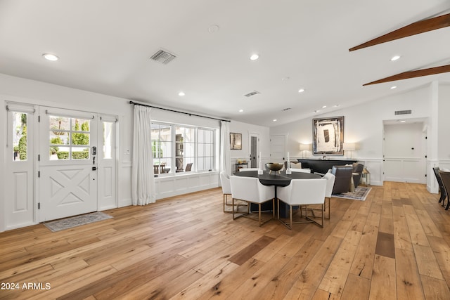 dining space with light hardwood / wood-style flooring and vaulted ceiling with beams