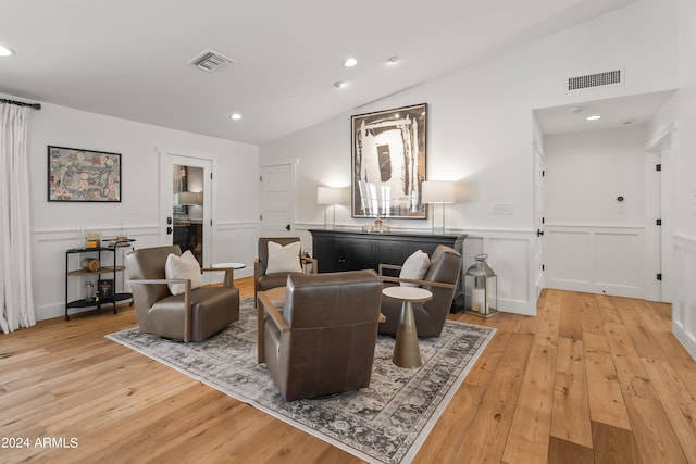 living room with light wood-type flooring and vaulted ceiling