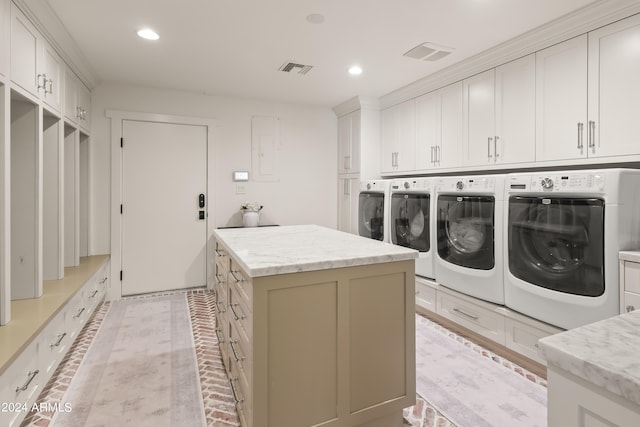 clothes washing area featuring washing machine and dryer and cabinets