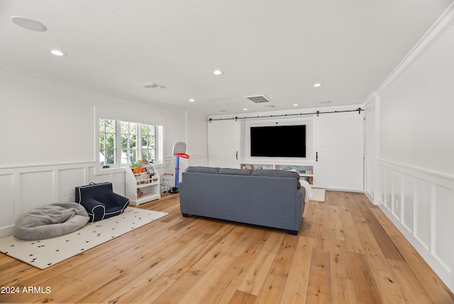 living room featuring light wood-type flooring, a barn door, and ornamental molding