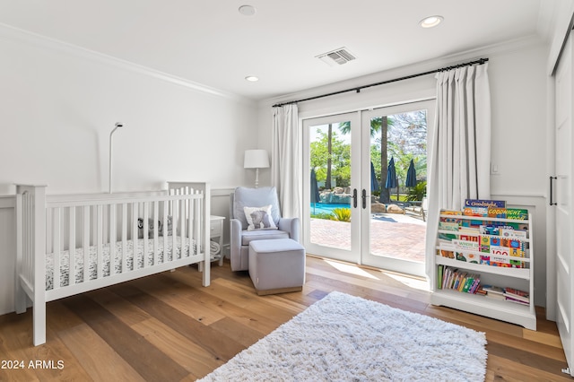 bedroom with wood-type flooring, crown molding, french doors, and access to outside