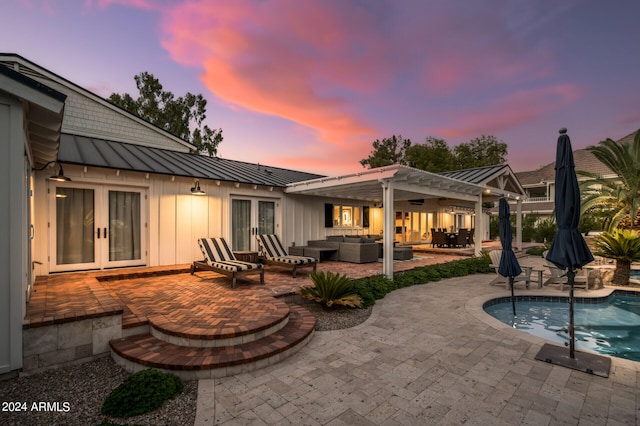 patio terrace at dusk with a pergola, outdoor lounge area, and french doors