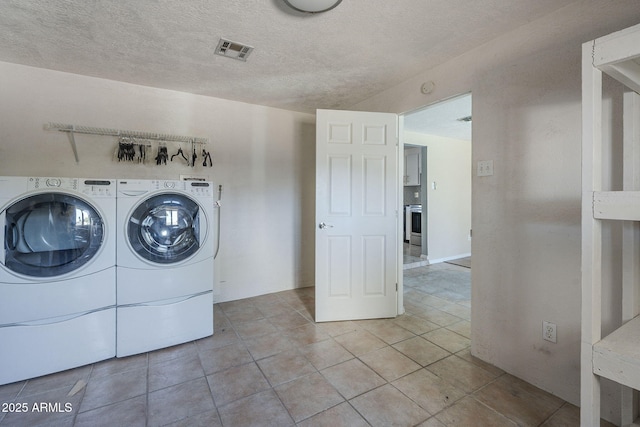 4025 E Surrey Ave, Phoenix, AZ 85032 - laundry area featuring independent washer and dryer, light tile patterned floors, and a textured ceiling