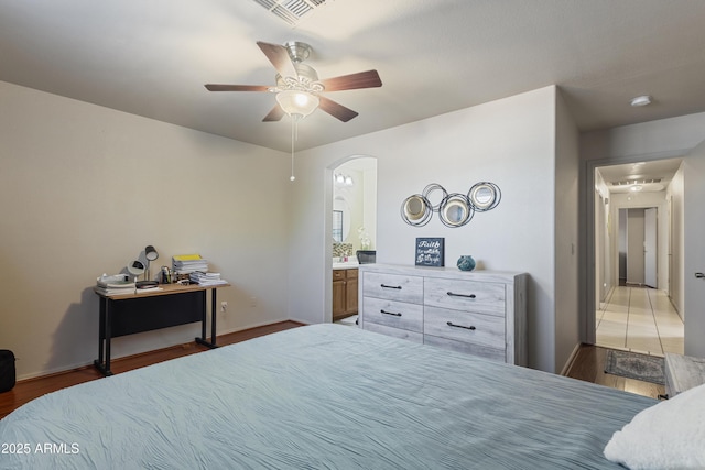 3534 N 106th Ln, Avondale, AZ 85392 - bedroom with wood finished floors, arched walkways, ceiling fan, and ensuite bathroom