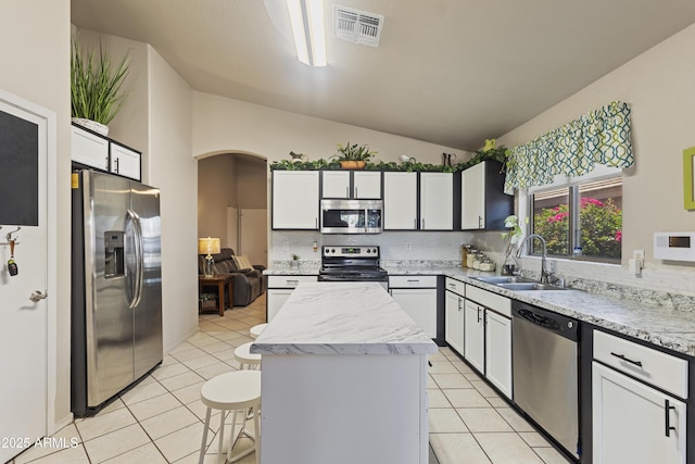 3534 N 106th Ln, Avondale, AZ 85392 - kitchen featuring stainless steel appliances, light tile patterned floors, a center island, tasteful backsplash, and vaulted ceiling