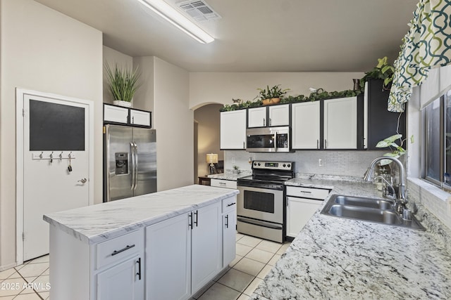 3534 N 106th Ln, Avondale, AZ 85392 - kitchen with appliances with stainless steel finishes, arched walkways, light tile patterned floors, a kitchen island, and decorative backsplash