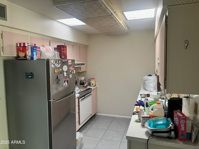 kitchen featuring light tile patterned floors, stainless steel refrigerator, white cabinets, and white range with electric stovetop