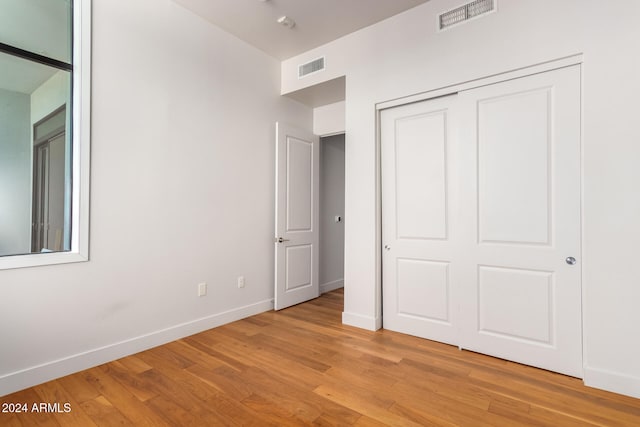 unfurnished bedroom with light hardwood / wood-style flooring and a closet