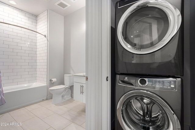 laundry area with light tile patterned flooring and stacked washer and dryer