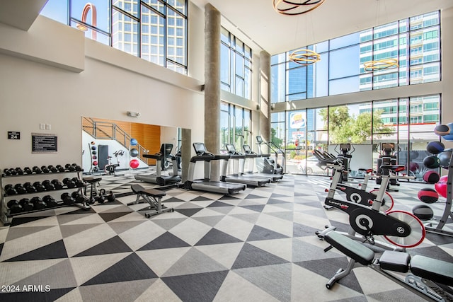 gym with a healthy amount of sunlight, a towering ceiling, and a chandelier