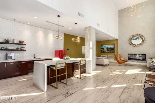 bar featuring light hardwood / wood-style floors, sink, hanging light fixtures, and a towering ceiling