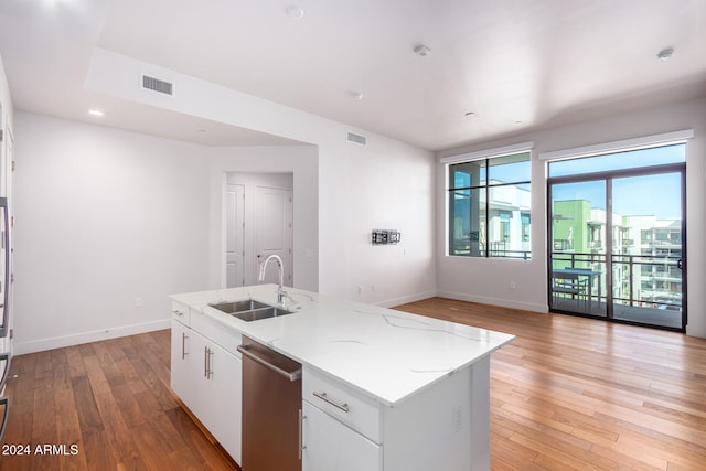 kitchen featuring a center island with sink, sink, white cabinets, and light hardwood / wood-style flooring