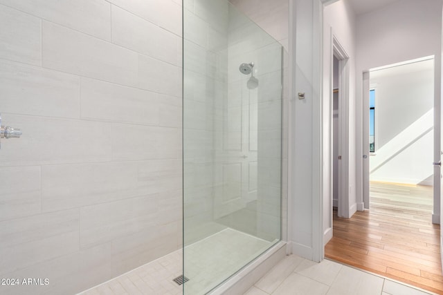 bathroom with a tile shower and hardwood / wood-style floors