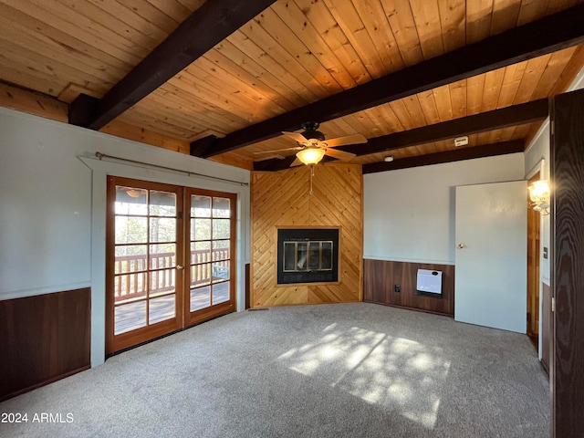 unfurnished living room featuring beam ceiling, carpet, wooden walls, and a fireplace