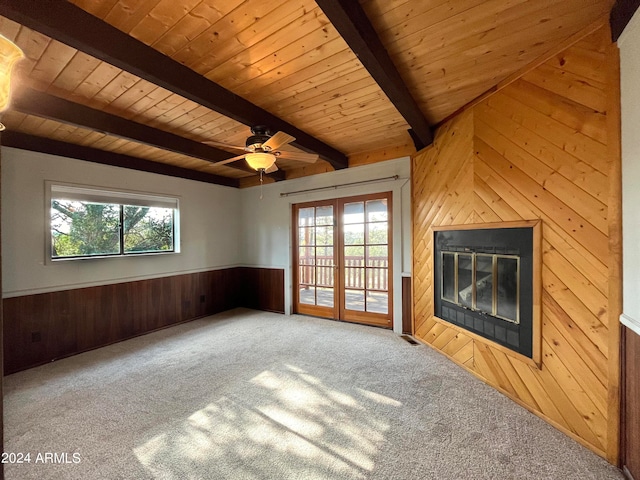 unfurnished living room with wood walls, wooden ceiling, lofted ceiling with beams, carpet flooring, and ceiling fan