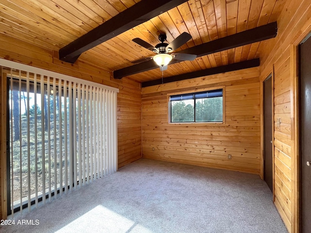 carpeted spare room with wood ceiling, ceiling fan, beamed ceiling, and wooden walls