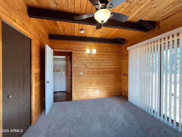 carpeted empty room with ceiling fan, beamed ceiling, wooden walls, and washing machine and clothes dryer