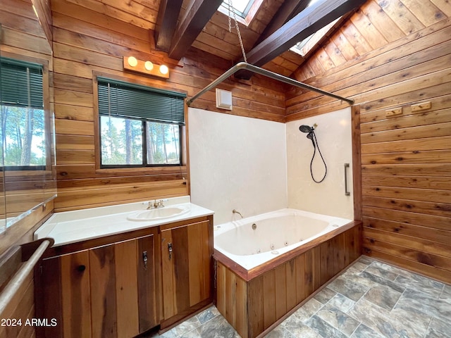 bathroom with a wealth of natural light, vanity, wooden walls, and vaulted ceiling with skylight