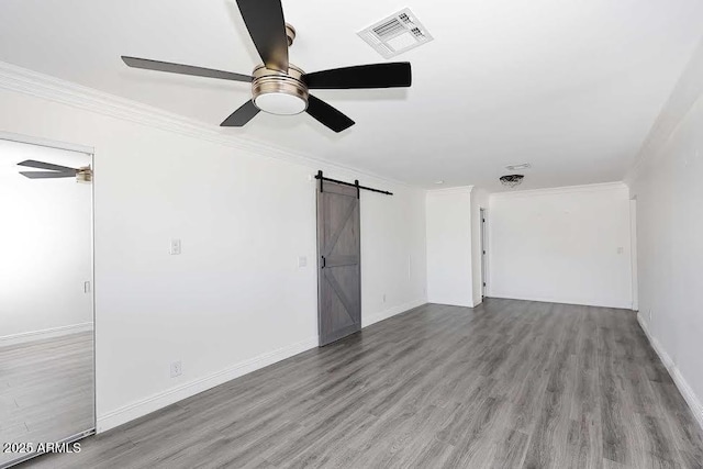 empty room featuring crown molding, light hardwood / wood-style flooring, and a barn door