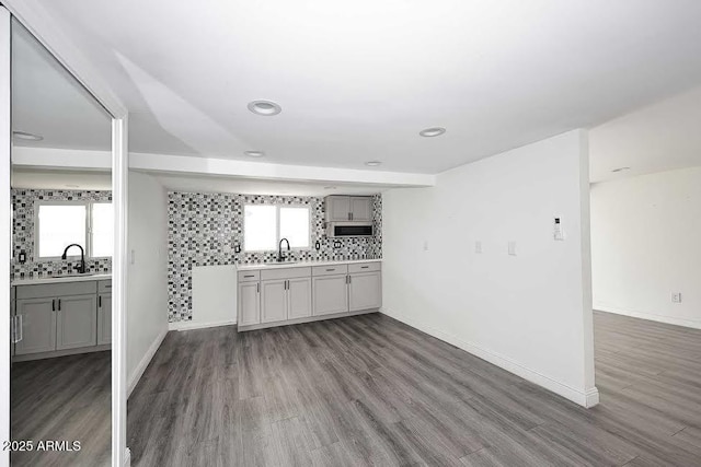 bar with gray cabinetry, sink, tasteful backsplash, and dark hardwood / wood-style flooring