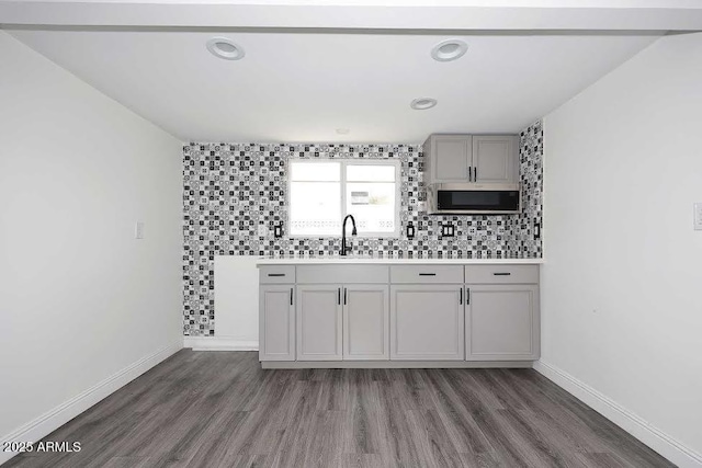 kitchen with gray cabinetry, sink, backsplash, and dark hardwood / wood-style flooring