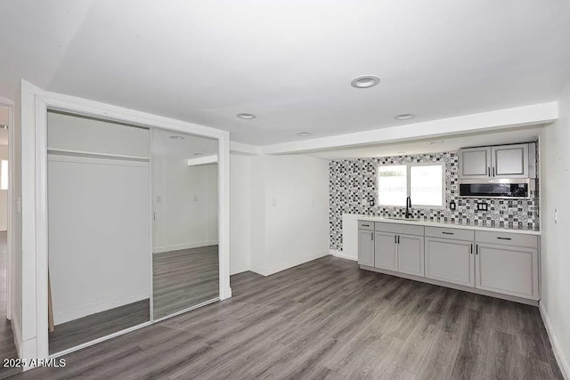 interior space featuring dark wood-type flooring, gray cabinets, sink, and decorative backsplash