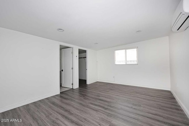 empty room with dark hardwood / wood-style flooring and an AC wall unit