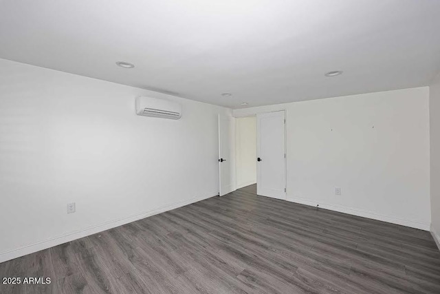 unfurnished room featuring a wall unit AC and dark hardwood / wood-style floors