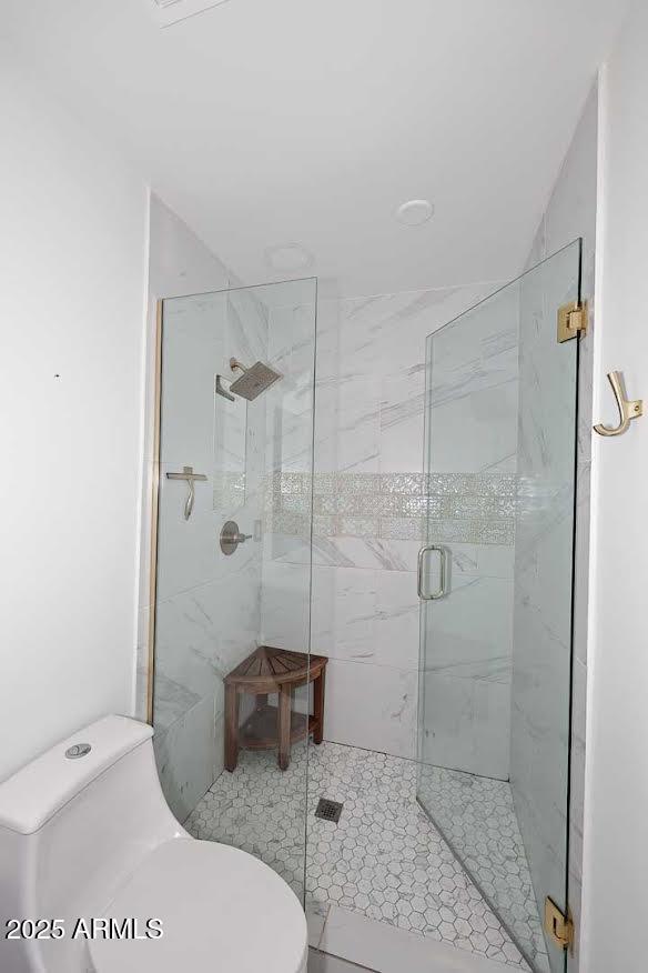 bathroom with toilet and a shower with shower door