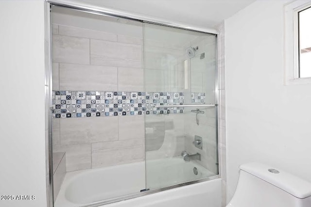 bathroom with combined bath / shower with glass door and toilet